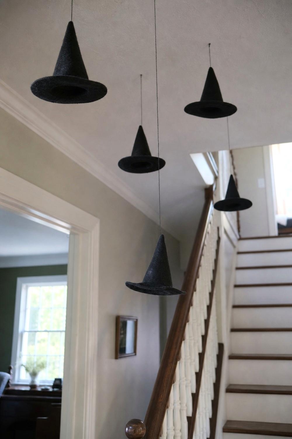 A cluster of black pointed hats hanging from the ceiling above an entryway