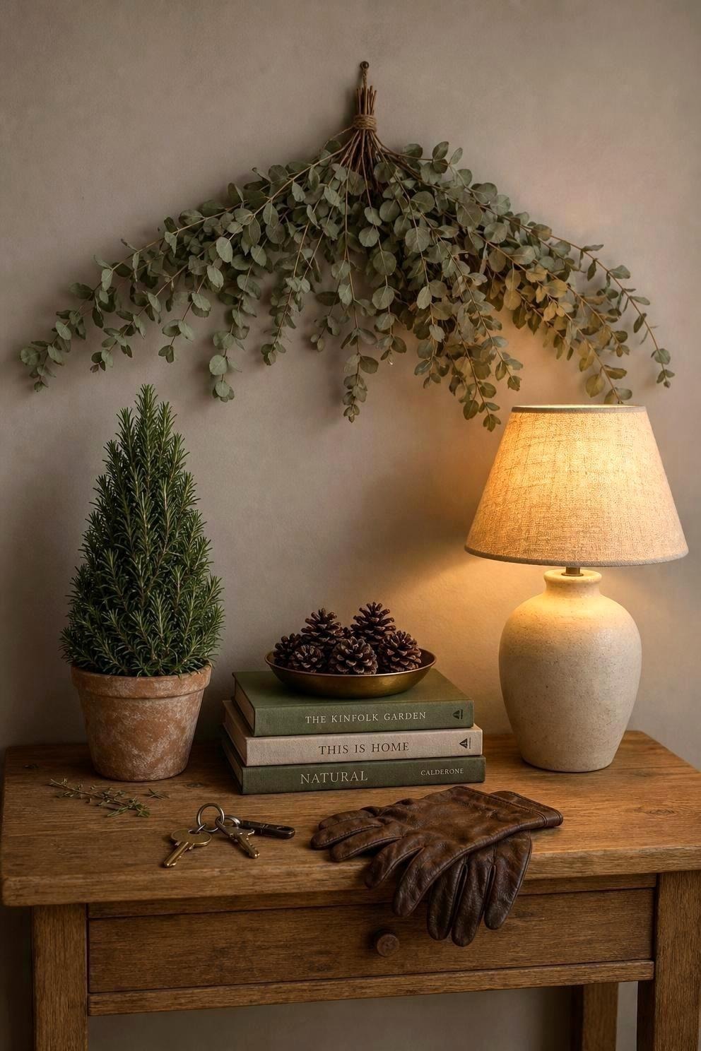 Clipped rosemary plant in a terracotta pot on a narrow console beside a eucalyptus swag