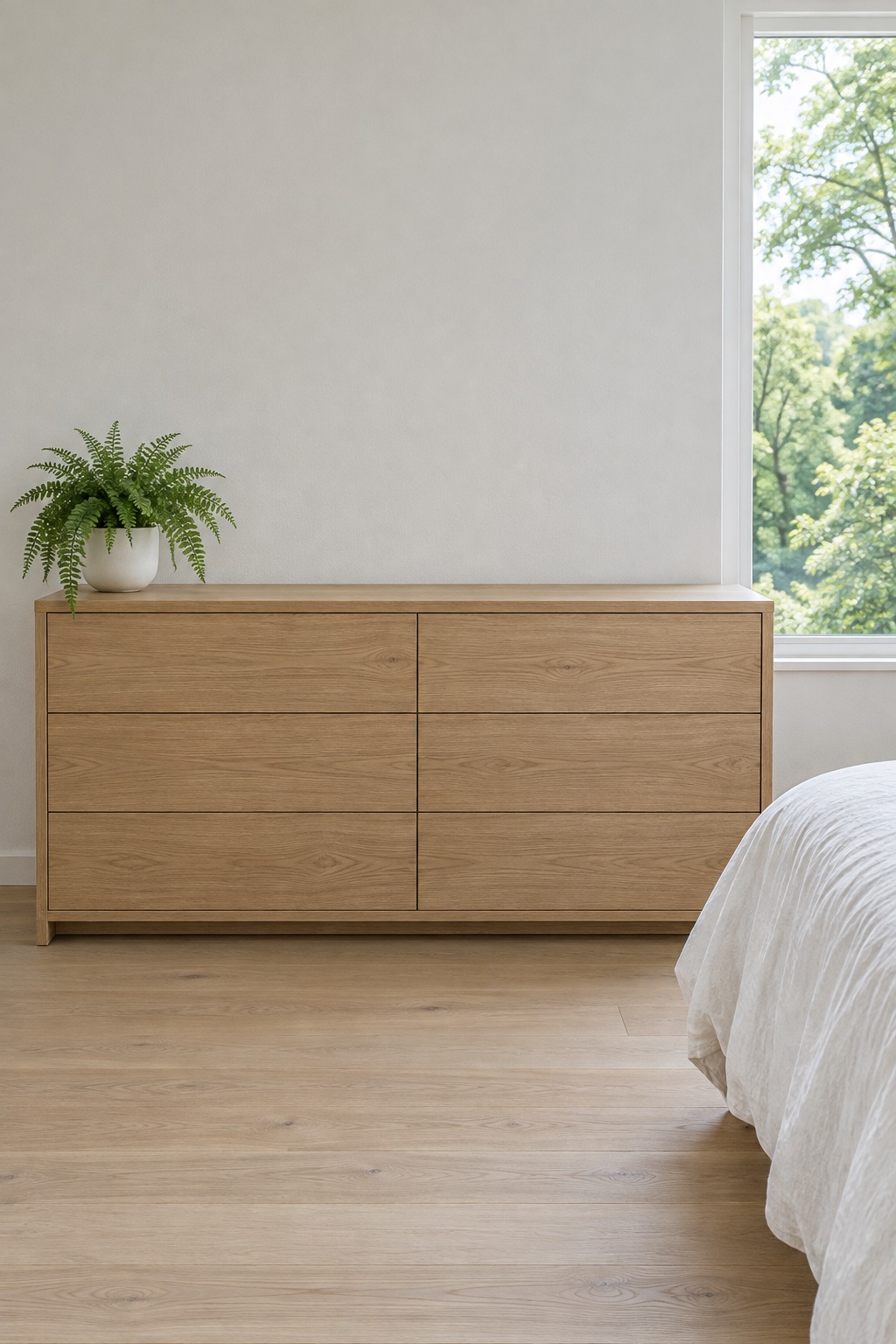Light oak dresser with a bare top and one small fern in a white pot