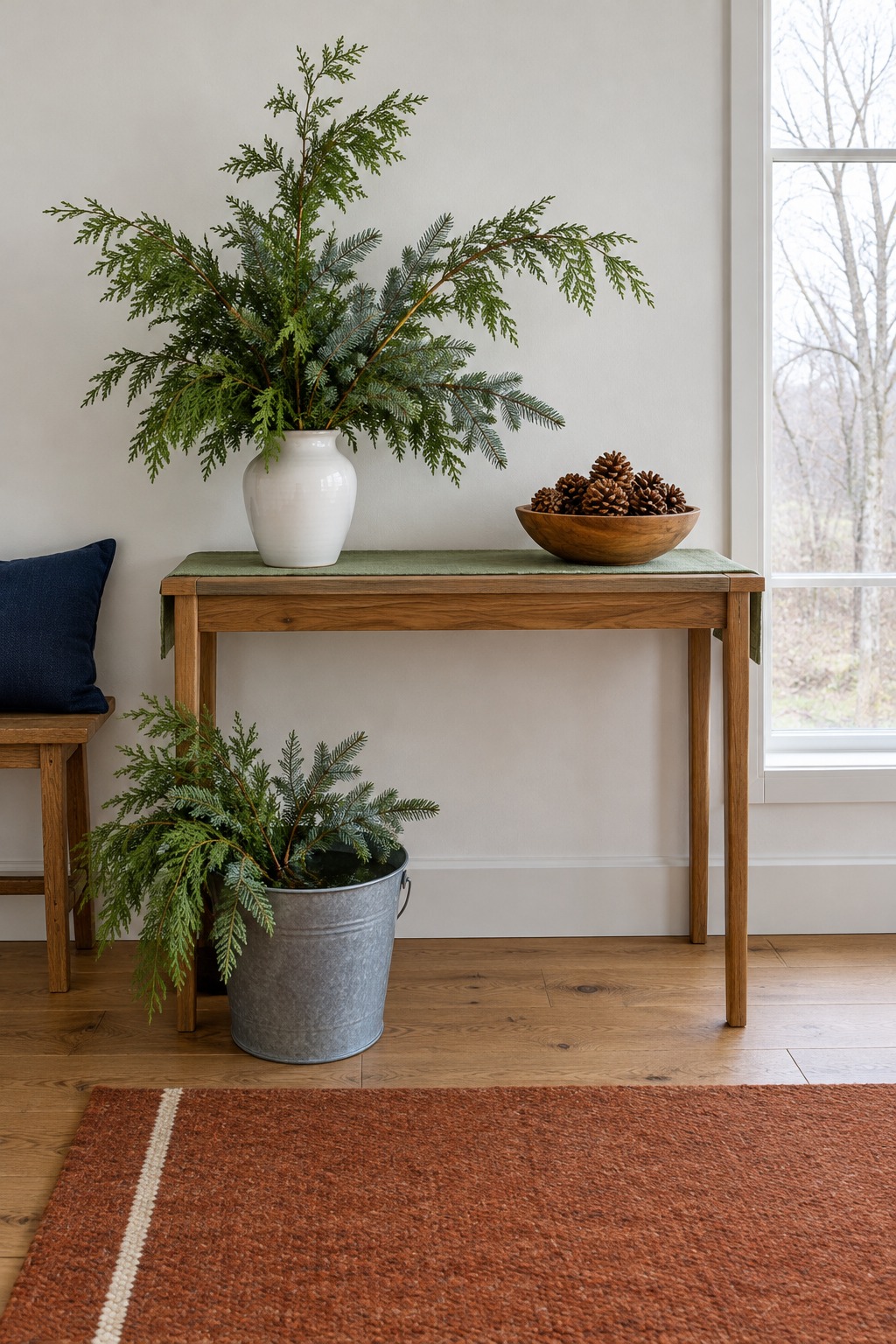 Vase and bucket of fresh cut cedar and noble fir branches on a hall console